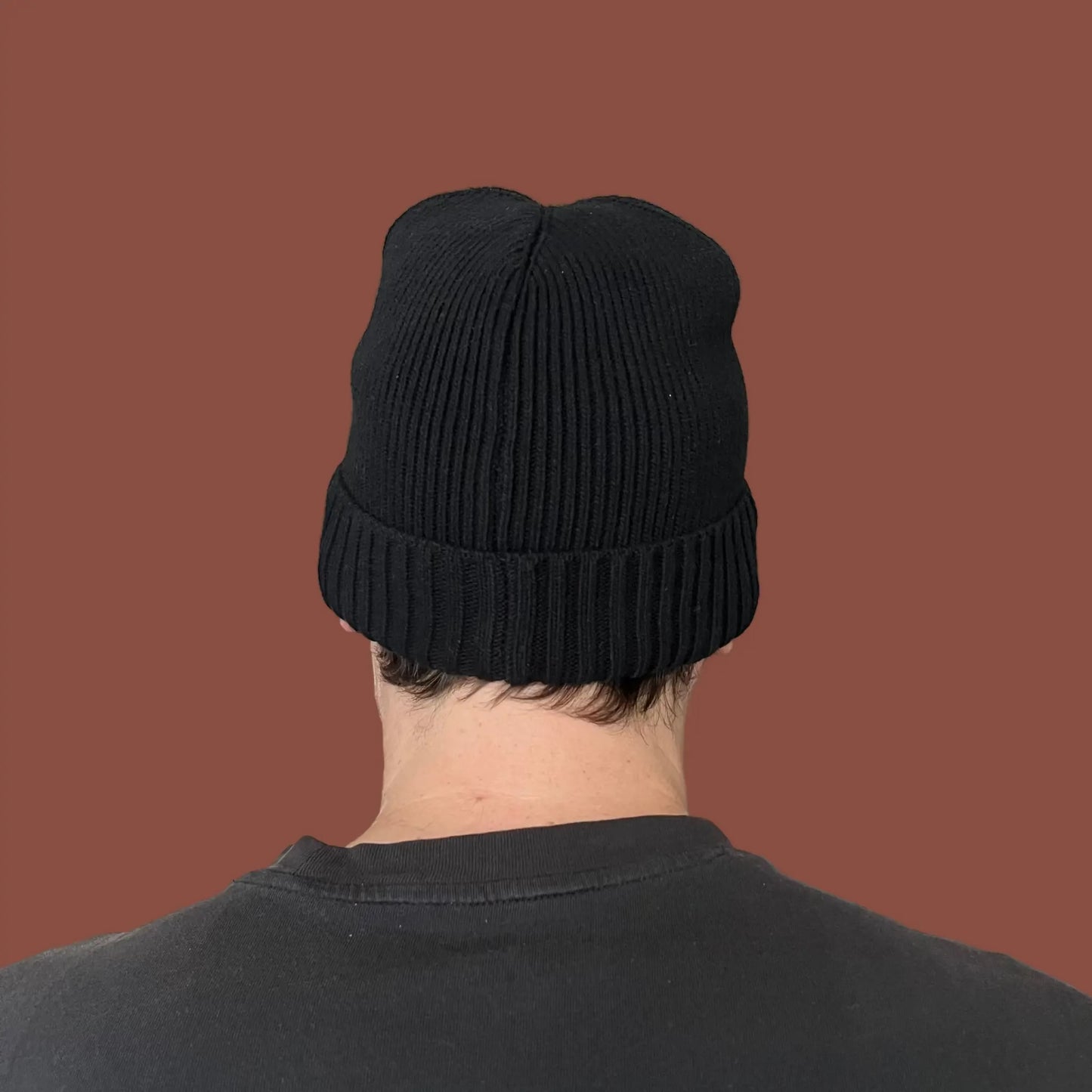 Model wearing a black knit beanie