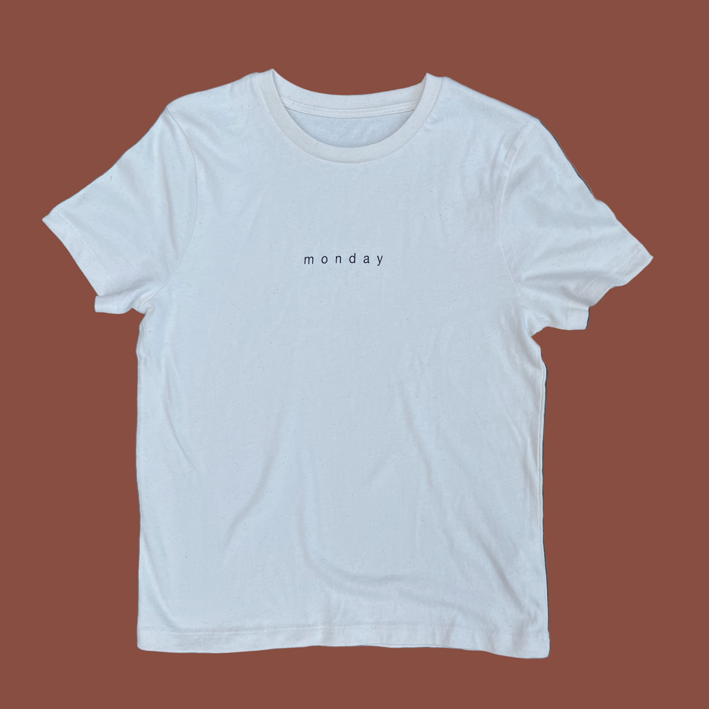 White t-shirt with 'monday' text on a gray background