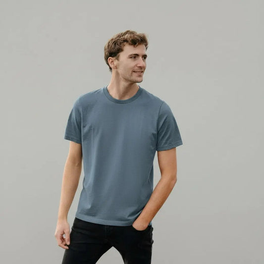 Man wearing a blue t-shirt against a gray background
