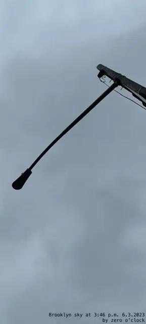 Two streetlights against a gray sky with text at the bottom.