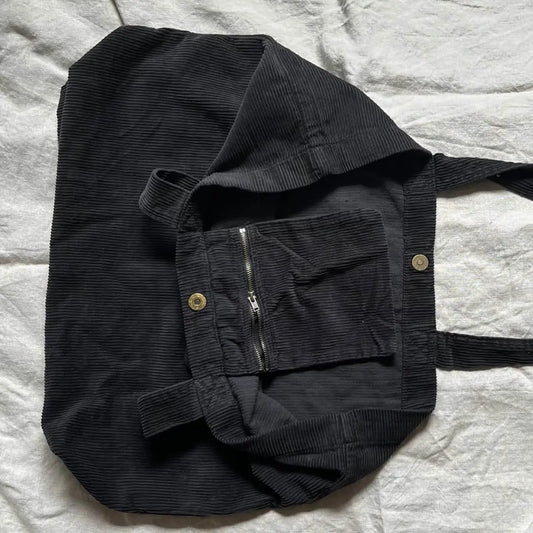 Black corduroy jacket with a hood on a light gray textured surface