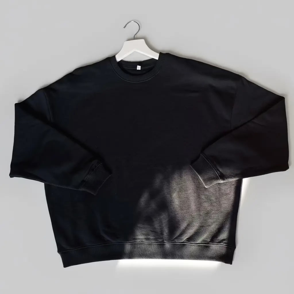 Black sweatshirt on a white hanger against a gray background