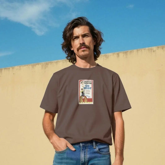 Man wearing a brown t-shirt with a graphic design against a blue sky and beige wall.