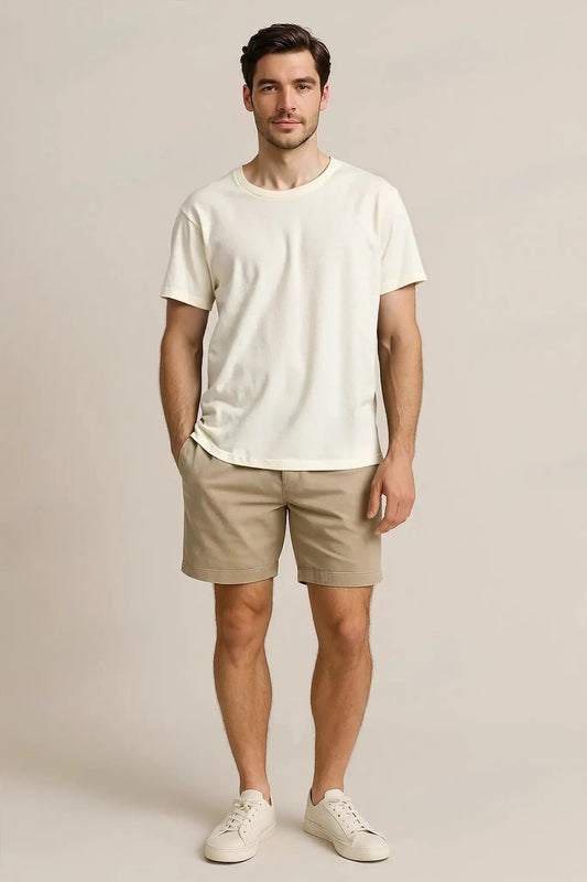 Man wearing a white t-shirt and beige shorts against a plain background