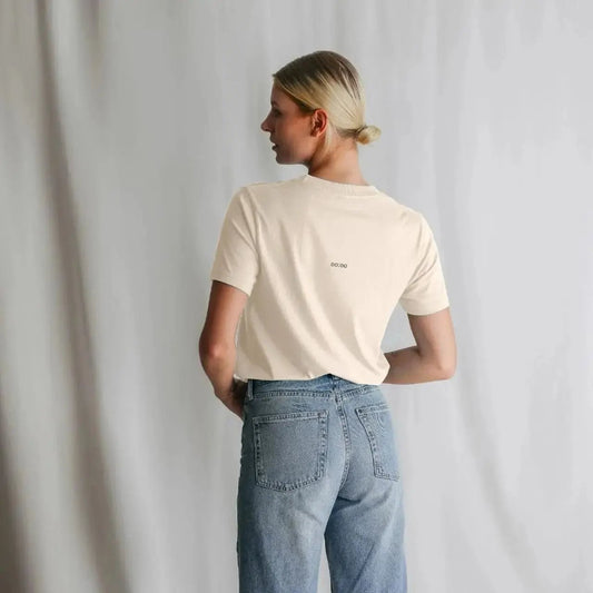 Person wearing a beige t-shirt and blue jeans against a plain background