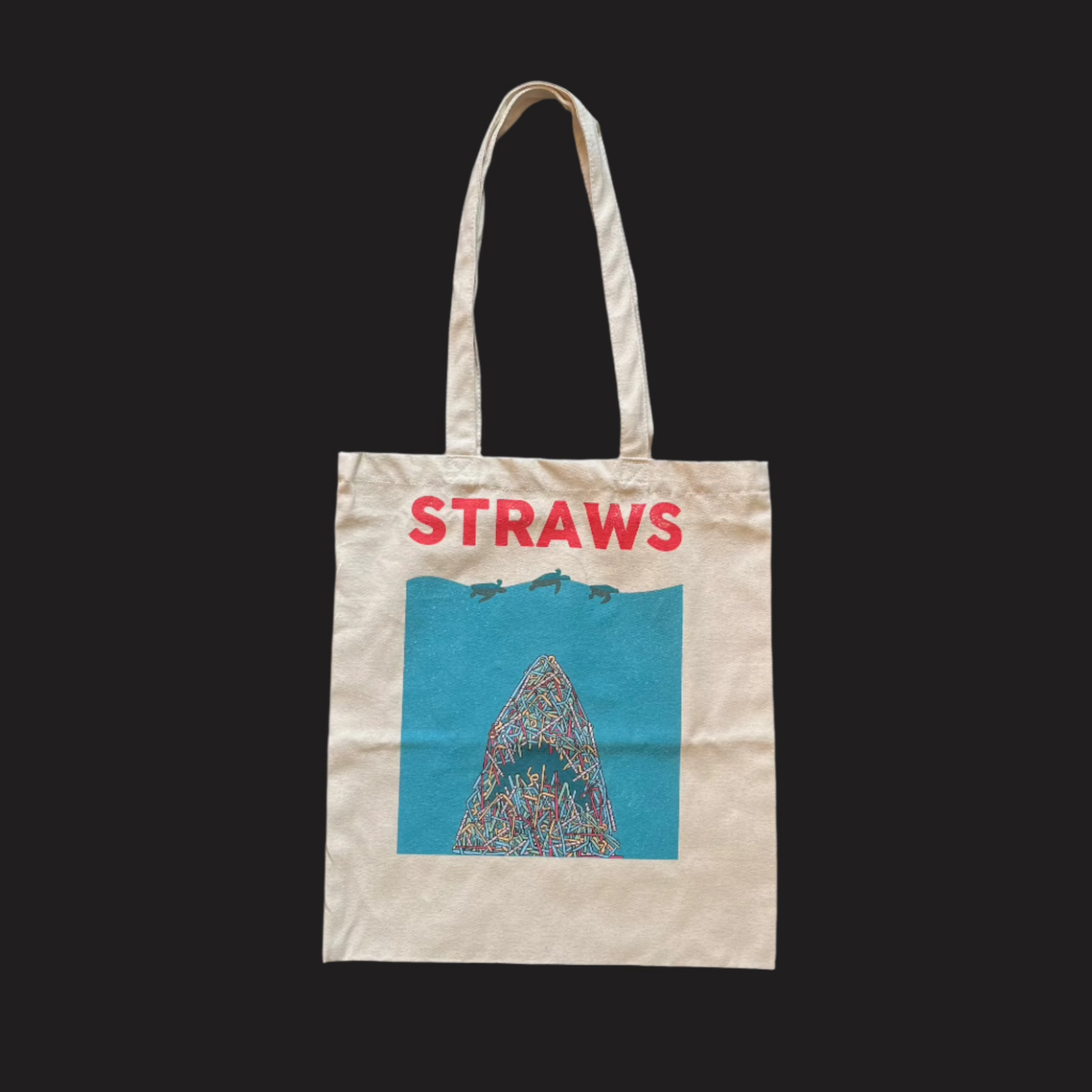 A beige organic cotton tote bag with 'STRAWS' and a shark graphic that resembles the poster of the film Jaws