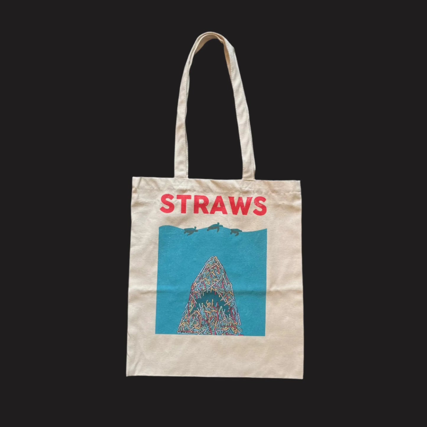 A beige organic cotton tote bag with 'STRAWS' and a shark graphic that resembles the poster of the film Jaws