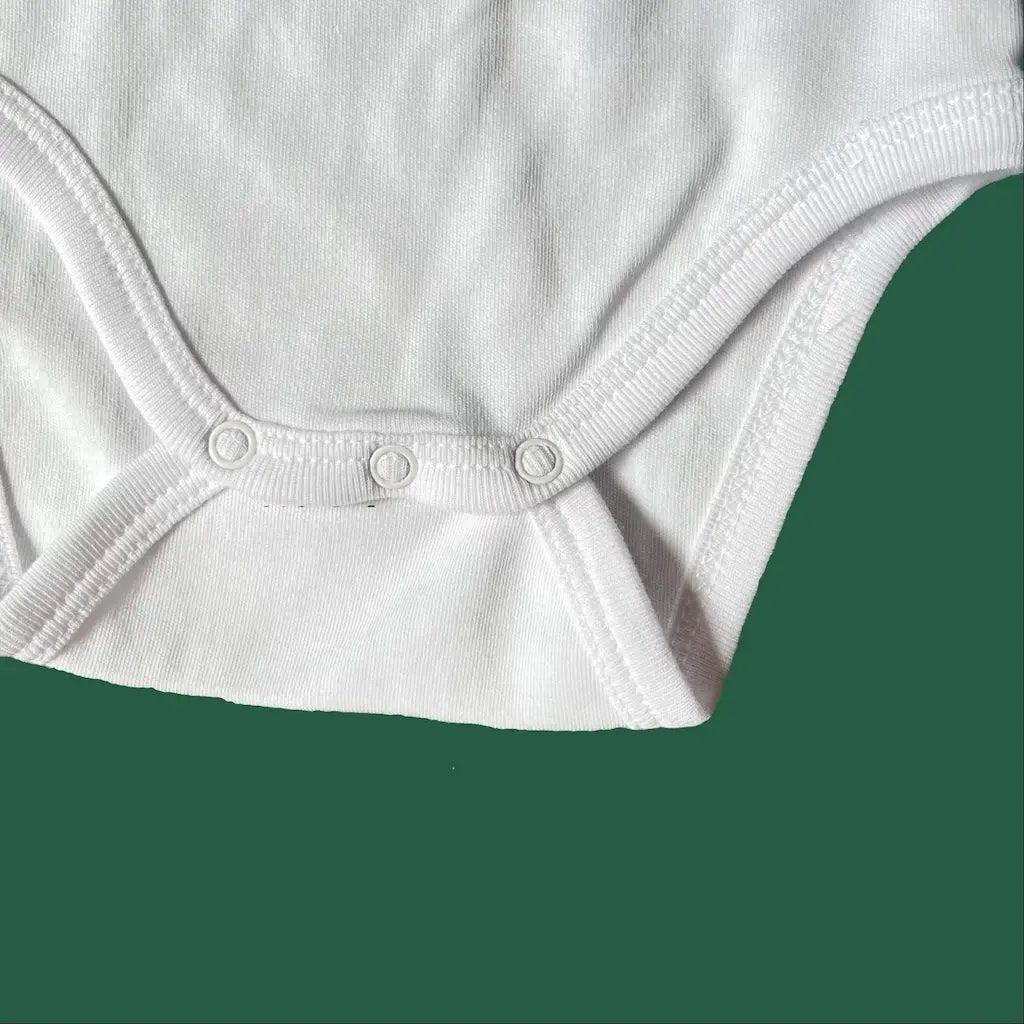 Close-up of a white baby bodysuit on a green background