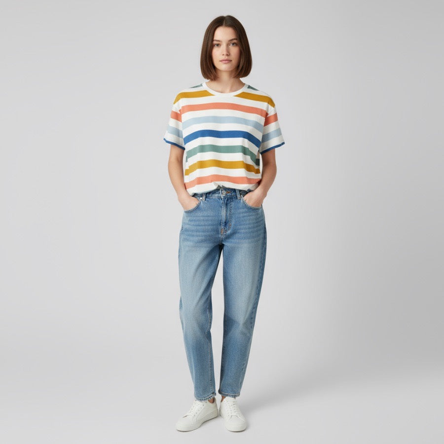 Person wearing a striped boxy tshirt and jeans on a plain background