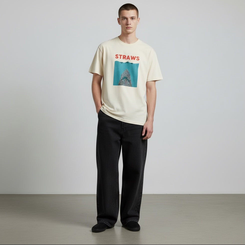 Man wearing a cream t-shirt with a graphic design and text, standing against a plain background