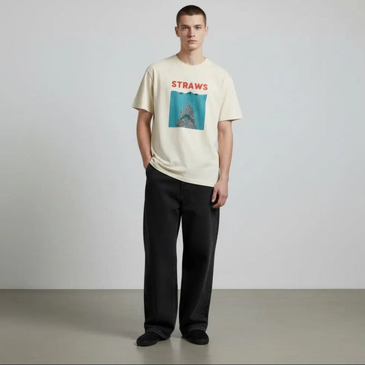 Man wearing a cream t-shirt with a graphic design and text, standing against a plain background