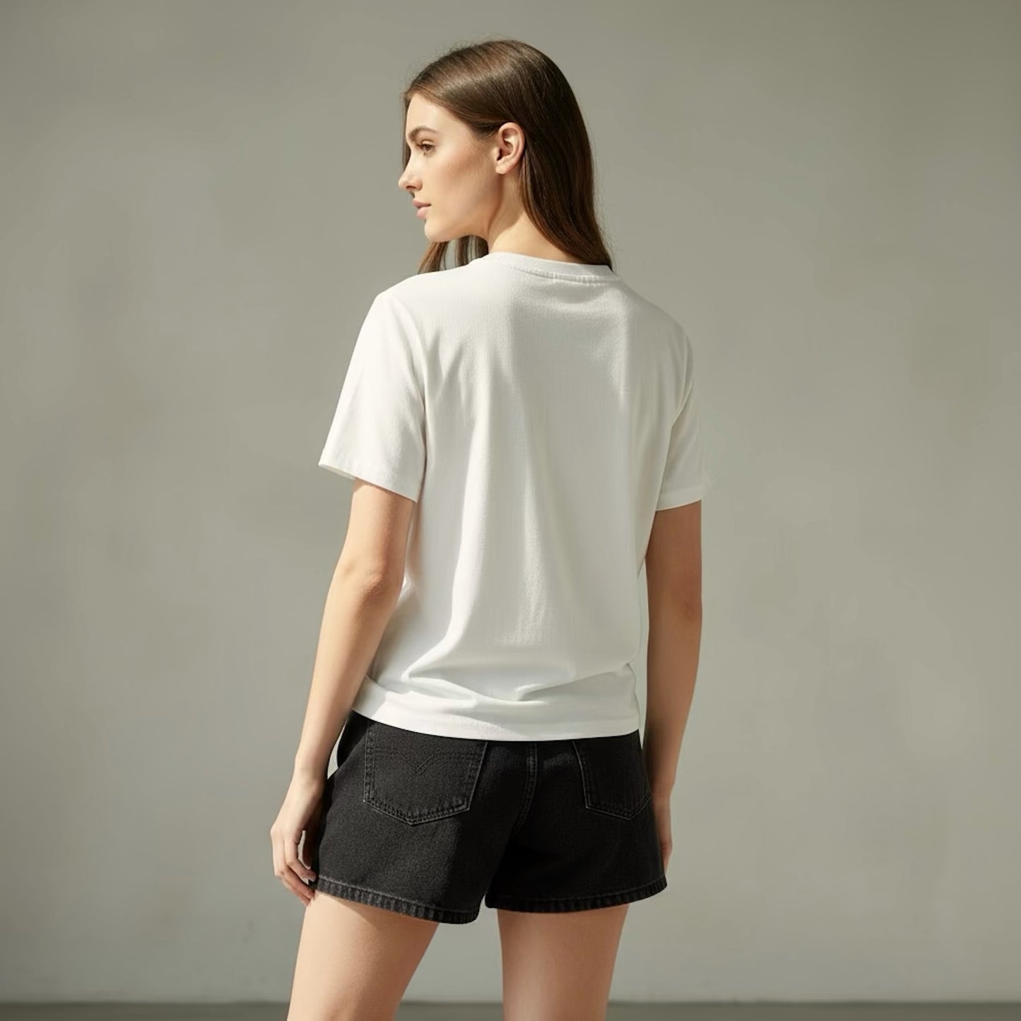 Woman wearing a white t-shirt and black shorts against a plain background
