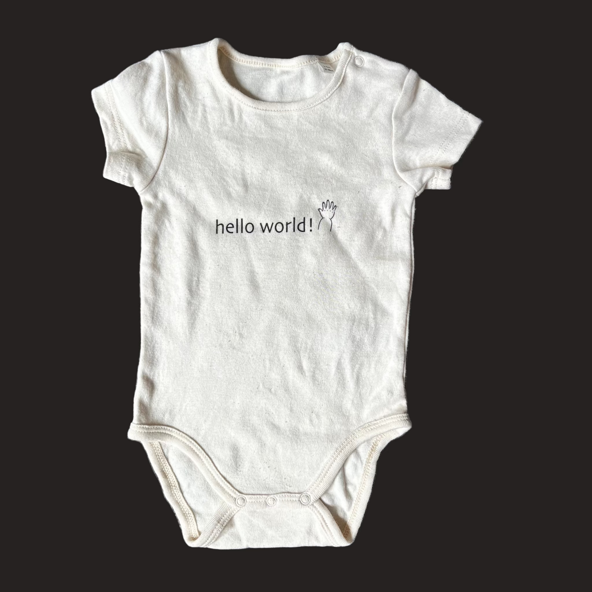 White baby onesie with 'hello world!' text