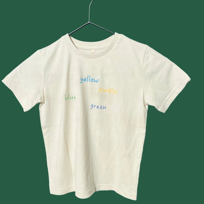 A oat cream kids' organic cotton tee with colorful text 'yellow blue green' printed across the front