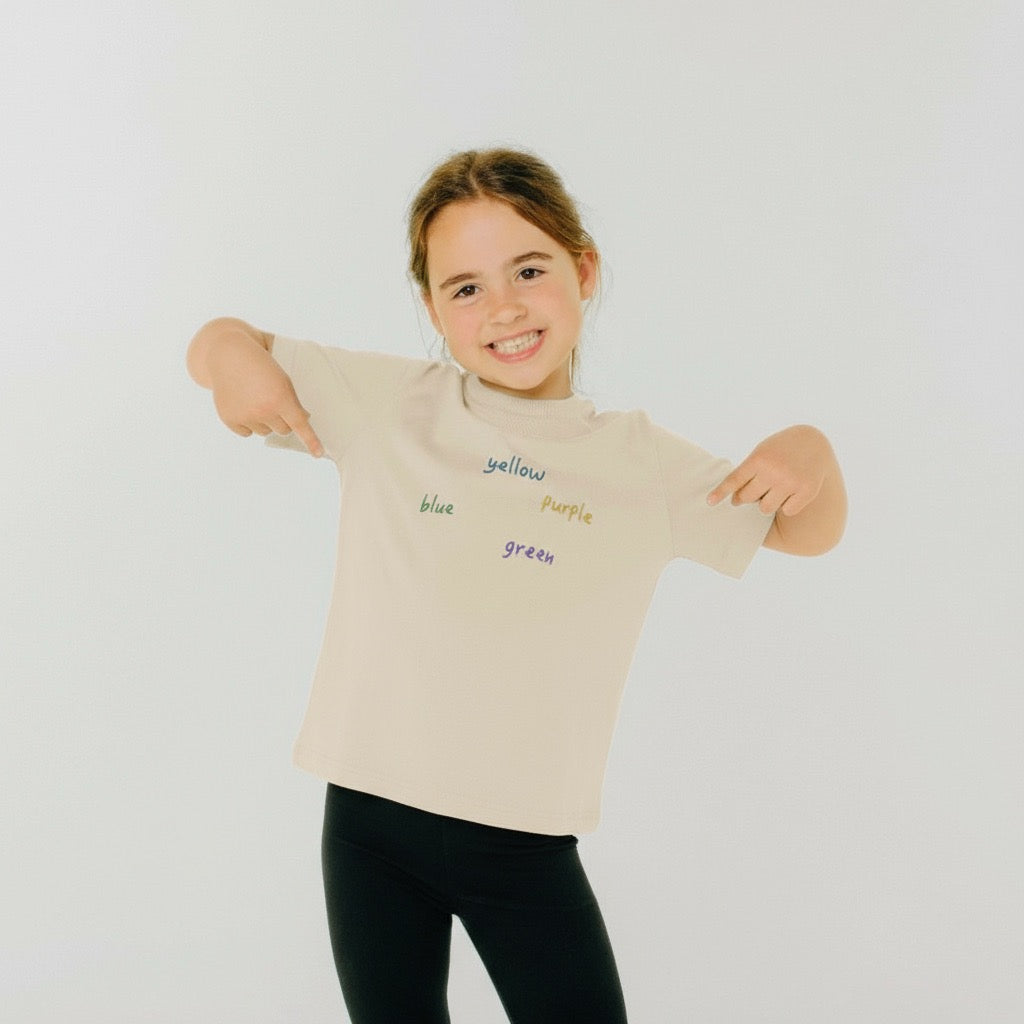 Child wearing a beige t-shirt with color words