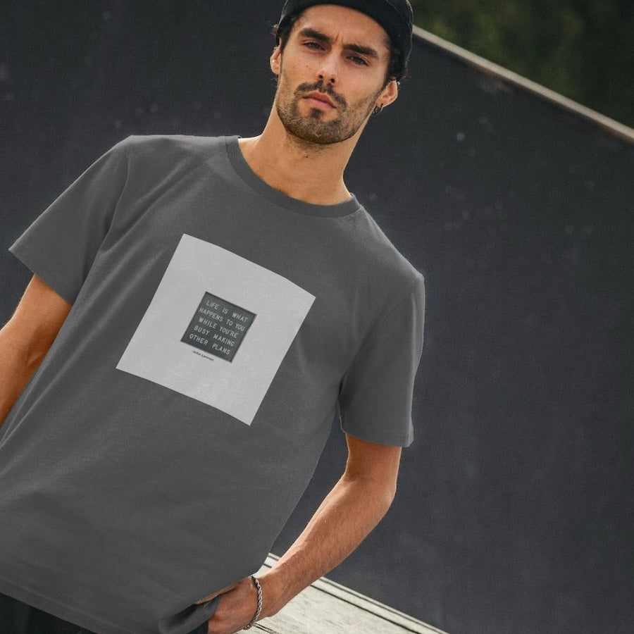 Man wearing a gray t-shirt with a graphic design on a dark background