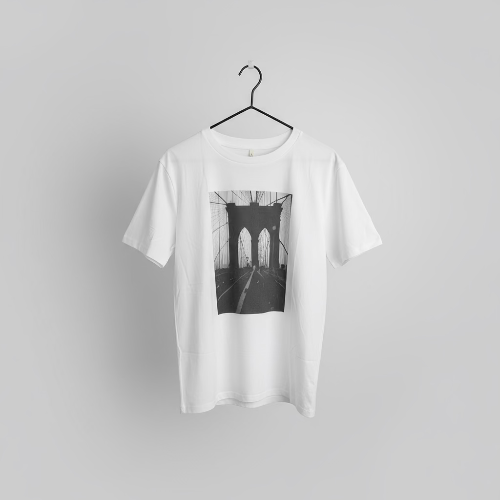 White t-shirt with a black and white brooklyn bridge picture on a hanger against a gray background