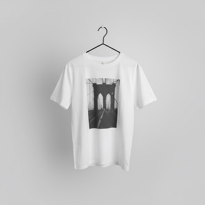 White t-shirt with a black and white brooklyn bridge picture on a hanger against a gray background