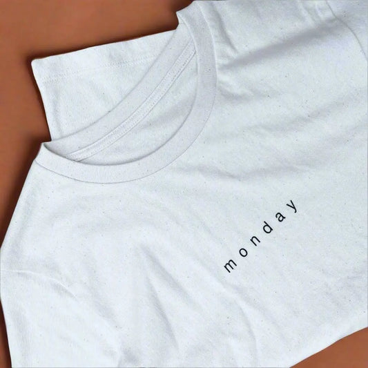 White t-shirt with 'monday' text on a brown surface