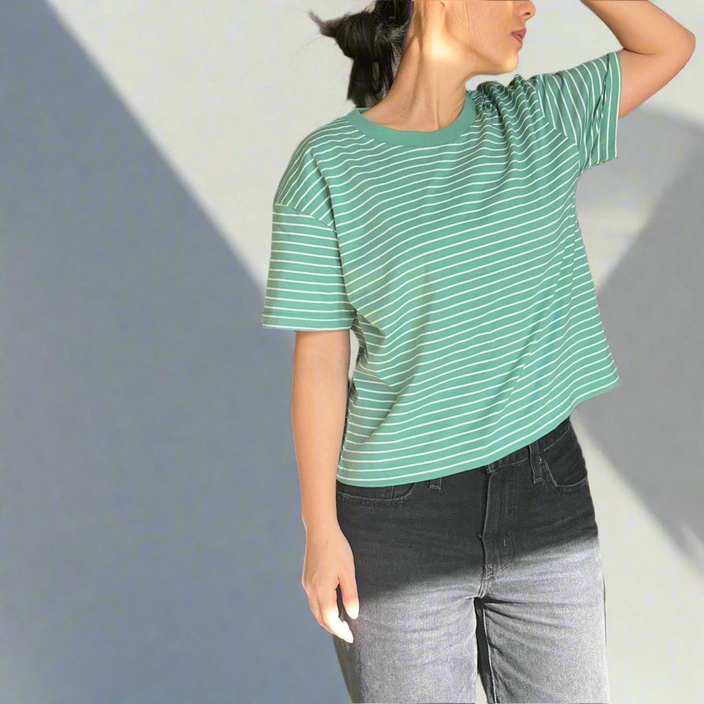 Person wearing a green and white striped tshirt against a plain background