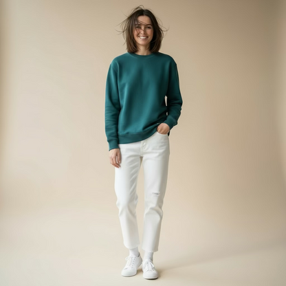 Person wearing a teal sweatshirt and white pants against a beige background