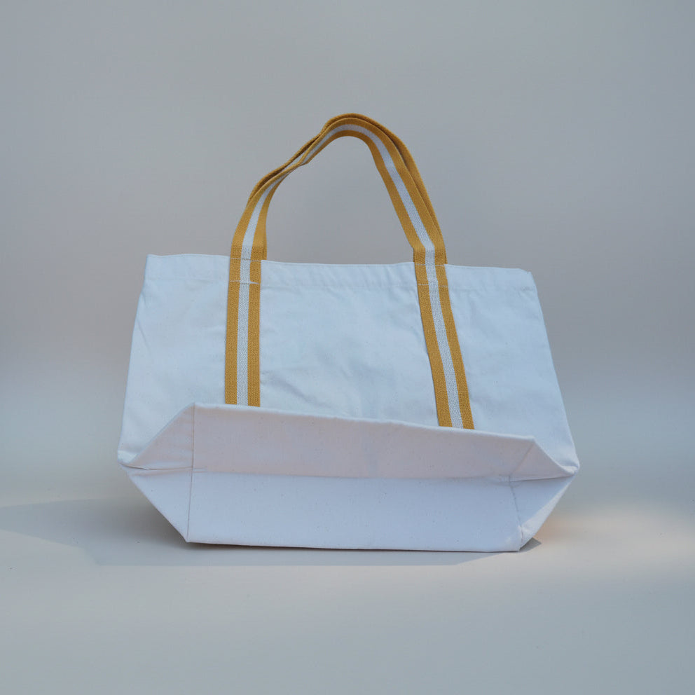 White tote bag with yellow handles on a light gray background