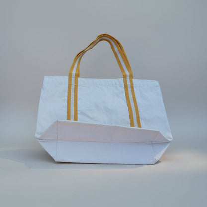 White tote bag with yellow handles on a light gray background