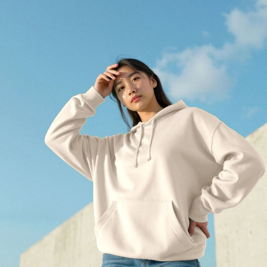 woman wearing a oat cream hoodie against a blue sky