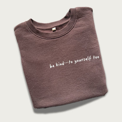 Folded brown sweatshirt with 'be kind...to yourself too' text